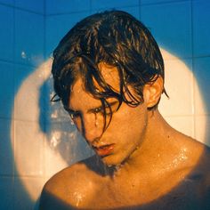 a man with wet hair standing in the shower