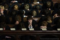 a group of people sitting in chairs with their backs to each other, covering their faces