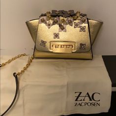 New With Tags Gold Leather Eartha Leather Mini Crossbody Bag From Zac Zac Posen Featuring A Detachable And Adjustable Shoulder Strap, A Top Flap Closure, An Internal Slip Pocket, An Embossed Internal Logo Stamp And Floral Appliqus. Condition New With Tag. Beautiful Neutral Colors But Quite A Statement Bag! Great For Any Outfit! Gold Party Bag With Branded Hardware, Designer Gold Bags With Silver-tone Hardware, Gold Evening Bags With Metal Hardware, Chic Tan Shoulder Bag With Chain Strap, Chic Gold Shoulder Bag With Silver-tone Hardware, Gold Clutch Bag With Silver-tone Hardware, Designer Tan Bags With Chain Strap, Tan Evening Bag With Silver-tone Hardware, Chic Tan Bag With Chain Strap