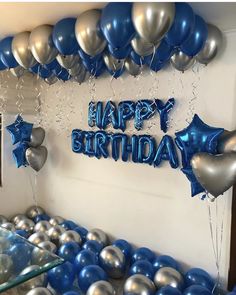 blue and silver balloons are on the wall in front of a happy birthday sign that reads,'happy birthday '