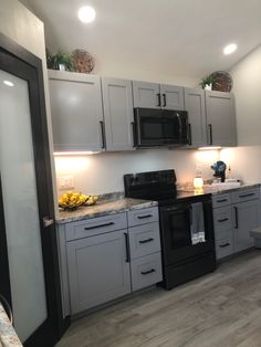 a kitchen with gray cabinets and black appliances