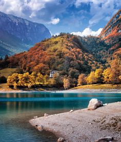 a lake surrounded by mountains and trees with autumn foliage on the hillsides in the background