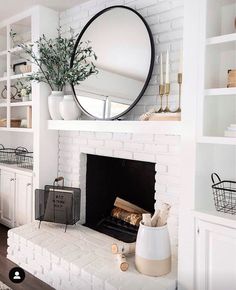 a white fireplace with a round mirror above it