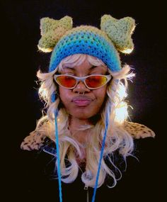 a woman with long blonde hair wearing sunglasses and a knitted cat ears hat on top of her head