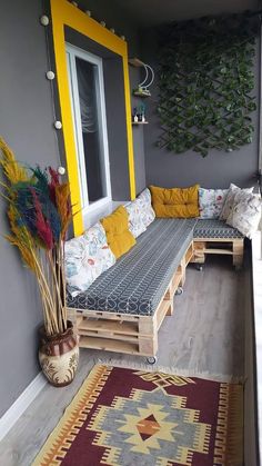 a couch made out of wooden pallets on top of a floor next to a window