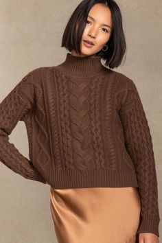 a woman wearing a brown sweater and tan skirt