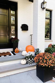 front porch decorated for halloween with pumpkins and flowers