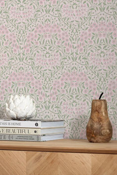 the books are stacked on top of each other next to a vase and flower wallpaper