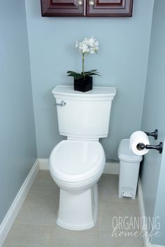 a white toilet sitting in a bathroom next to a roll of toilet paper on the floor