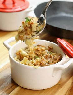 a spoon full of macaroni and cheese being lifted from a casserole dish