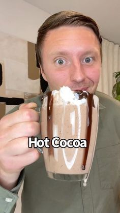 a man is holding a chocolate drink in his hand and has the words hot cocoa on it