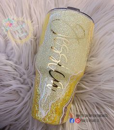 a gold glitter tumbler sitting on top of a white fur covered floor next to a stuffed animal