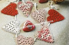 crocheted ornaments are arranged on a table with red and white hearts hanging from them