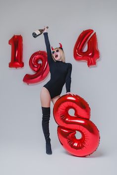 a woman in a black bodysuit and red balloons with the number six on it