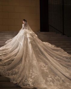 a woman in a wedding dress is standing on some steps with her long veil draped over her shoulders