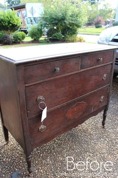 an old wooden dresser is sitting on gravel