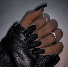 a woman's hand with black stiled nails and ring on her finger, wearing a leather glove