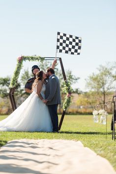 a bride and groom kissing under a checkered flag