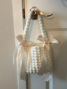 a door hanger made out of white yarn and ribbon