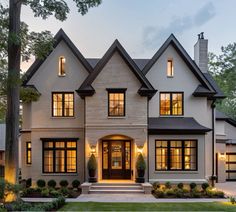 a large white house with lots of windows and lights on the front door is lit up at night