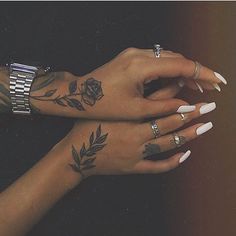 two women's hands with tattoos and rings on their fingers, both holding each other