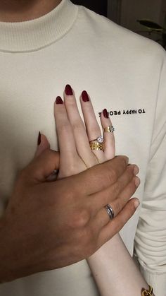 two people holding each other's hands with rings on their fingers and one wearing a sweater