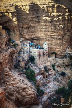 an aerial view of some buildings on the side of a cliff in a canyon area