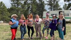 a group of women standing next to each other on top of a grass covered field