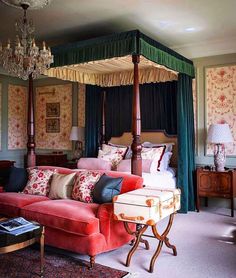 a canopy bed sitting in the middle of a bedroom next to a couch and coffee table