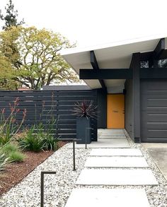 a modern house with black siding and yellow door