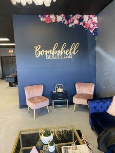 two chairs and a table in front of a blue wall with flowers on the side