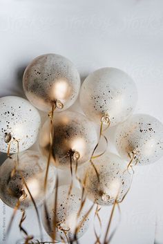 some white and gold balloons are in a vase by the wall with lights on them