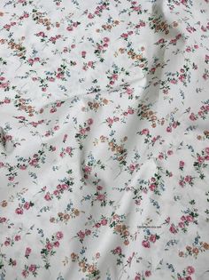 a white floral print fabric with pink, blue and green flowers on the bottom half