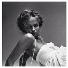 a black and white photo of a woman in a dress with pearls on her neck