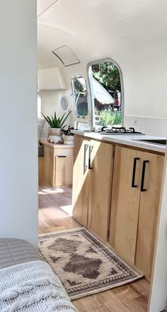 the inside of a camper with wood cabinets and rugs on the floor in front of it