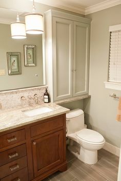 a white toilet sitting next to a sink in a bathroom under a vanity and mirror