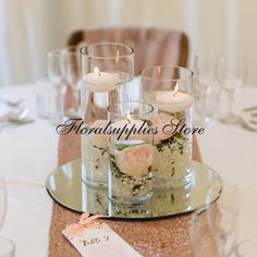 the centerpieces are arranged in glass vases with flowers and candles on top