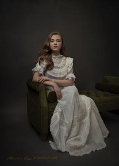 a woman in a white dress sitting on a green chair