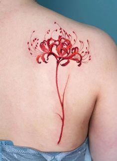 a woman's back tattoo with red flowers on her left shoulder and the top part of her upper arm