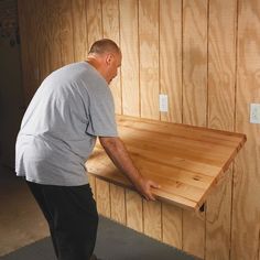 a man standing next to a wooden shelf in a room with wood paneling on the walls