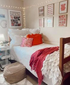 a bed with white sheets and red pillows in a room decorated with pictures on the wall