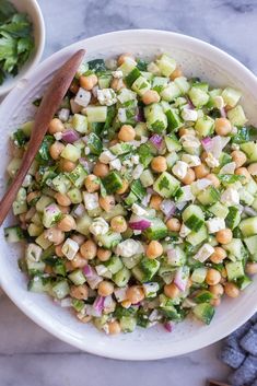 a white bowl filled with cucumber, chickpeas and red onion salad