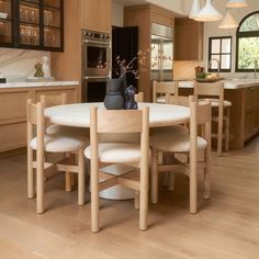 a kitchen table with four chairs and a vase on the table in front of it