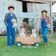 two people standing in front of a chicken coop with hay and fake chickens on it