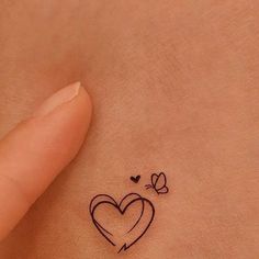 a small heart tattoo on the back of a woman's stomach