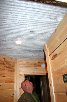 a man is standing in the corner of a room with wood paneling on the ceiling