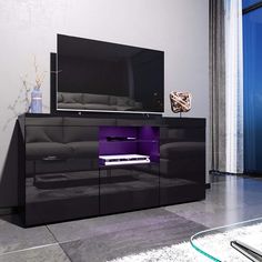 a living room with a large tv on top of a black entertainment center next to a window