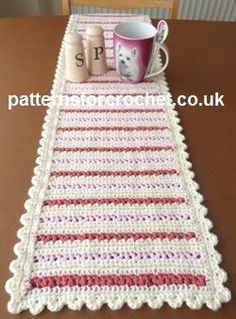 a crocheted table runner with coffee mugs on it