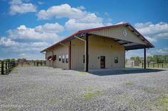 a large building with a red roof and two doors on the side of it in an open field