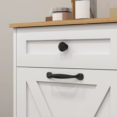 a white cabinet with black handles and knobs